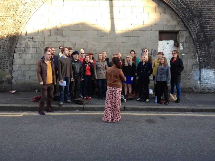 The Pop-Up Choir warming up outside Brixton East